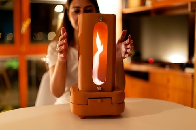 A woman is holding a candle in front of a table, creating warmth and ambiance.
